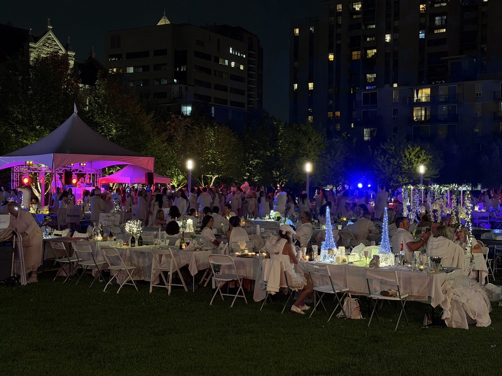 Dinner en Blanc guests at night under coloured event lighting
